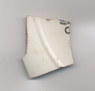 Fragment of white glazed ceramic pottery with partial maker's mark