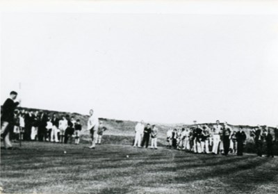 Golfers putting with a crowd of followers