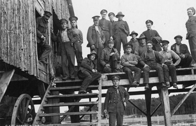 CFC troops posing on timber staging beside hut