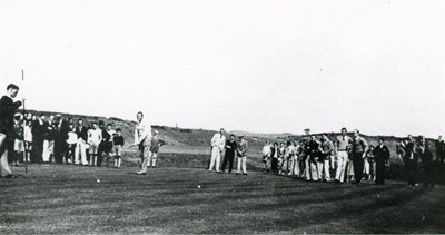 Golfer putting surrounded by spectators