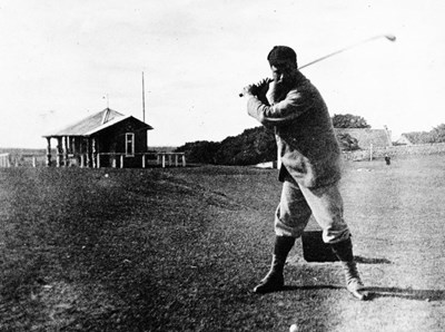 Golfer teeing off adjacent to ladies clubhouse 