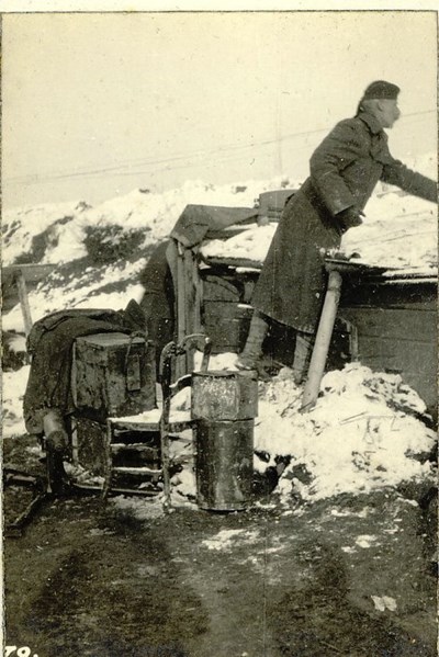 Colonel Robertson scrapes snow from the roof of H.Q.’s Hut