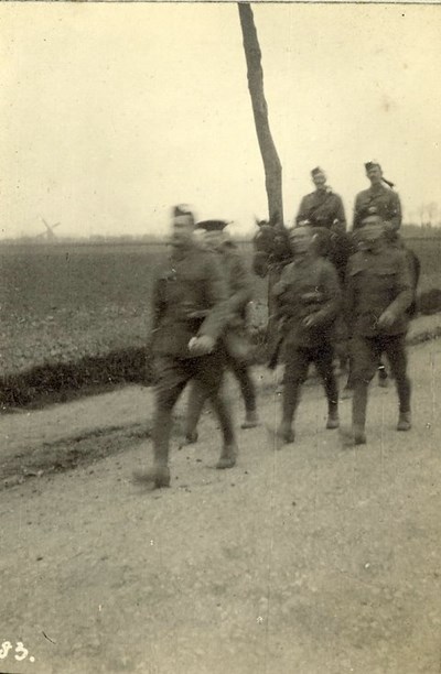Soldiers marching with officers behind mounted