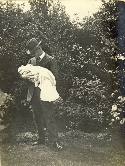 Capt. Rose (?)  in a garden setting,  holding a baby