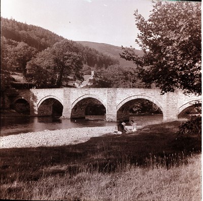 Family group sitting by a river bridge