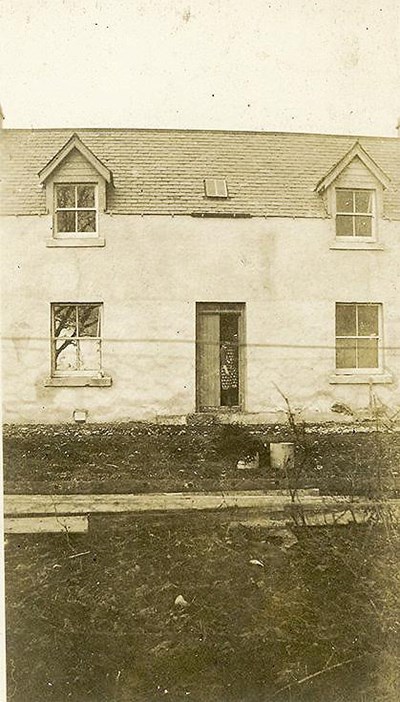 Lady at the door of two-storey house 'Three Trees'