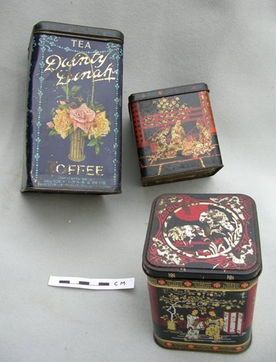 Three decorated tins used for golf workshop accessories